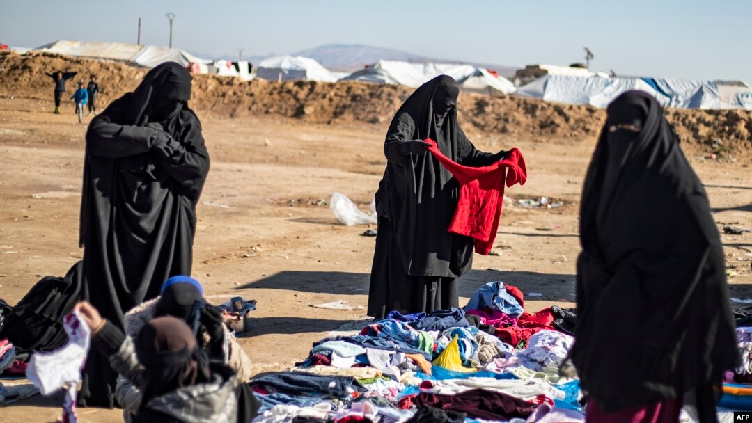 Para perempuan membongkar baju-baju bekas di luar kamp al-Hol, tempat pengungsian keluarga mantan kombatan ISIS, di wilayah al-Hasakeh, timur laut Suriah, pada 14 Januari 2020. (Foto: AFP) 