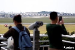 人们在日本南部冲绳岛的观景台遥望嘉手纳空军基地机场。（2018年3月24日）