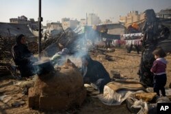 FILE - Palestinians displaced by the Israeli bombardment of the Gaza Strip cook at the makeshift tent camp in the Muwasi area on December 18, 2023.