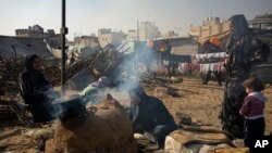 Palestinians displaced by the Israeli bombardment of the Gaza Strip cook at the makeshift tent camp in the Muwasi area on Monday, December 18, 2023. 