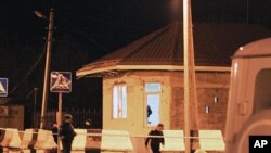 Investigators pass a damaged police check point in the village of Karabudakhkent, 30 kilometers (18 miles) south of the provincial capital, Makhachkala, Russia, March 6, 2012.