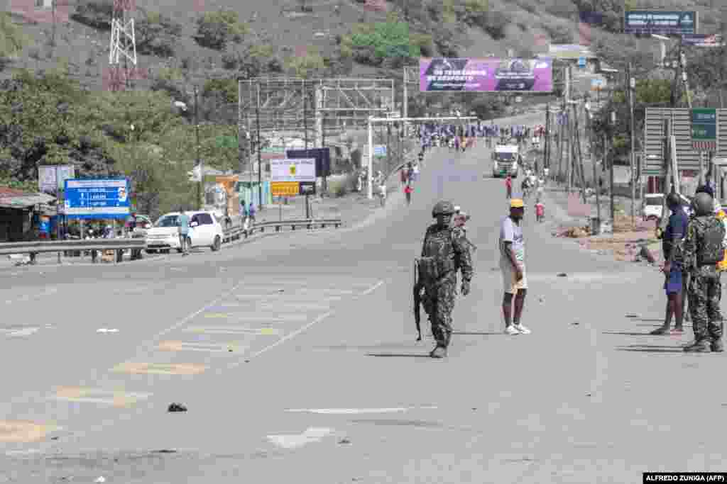 Soldados moçambicanos caminham na estrada onde os manifestantes se reúnem em direção ao posto fronteiriço de Ressano Garcia, entre Moçambique e África do Sul, em 13 de novembro de 2024.