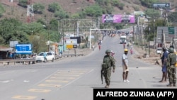 Soldados moçambicanos caminham na estrada onde os manifestantes se reúnem em direção ao posto fronteiriço de Ressano Garcia, entre Moçambique e África do Sul, em 13 de novembro de 2024.