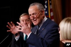 Senate minority leader, Charles Schumer, D-NY.,at podium gestures as Sen. Dick Durbin, D-Il., left, and Sen. Patty Murray, D-Wash., right, listen during a news conference in the Senate media room at the Capitol, Jan. 21, 2020, in Washington.