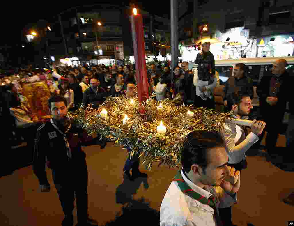 Syrian scouts carry a large candle during a vigil for civilians and security officers killed in Saturday explosions in  Damascus.  (AP) 