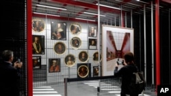 A person takes pictures of paintings at the Louvre Conservation Center, which was inaugurated in Lievin in northern France, Tuesday Oct.8, 2019.