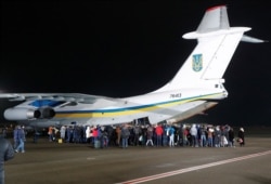 Relatives of Ukrainian citizens, who were exchanged during a prisoner swap, surround an aircraft during a welcoming ceremony at Boryspil International Airport, outside Kyiv, Ukraine, Dec. 29, 2019.