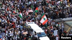 Uma pessoa segura uma bandeira libanesa enquanto as pessoas se reúnem em frente ao parlamento da África do Sul durante um protesto para mostrar apoio aos palestinianos na Faixa de Gaza, na Cidade do Cabo, África do Sul, 5 de outubro de 2024.