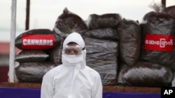 A police wearing a personal protective equipment stands in front of seized illegal drugs before being burnt during a destruction ceremony to mark International Day against Drug Abuse and Illicit Trafficking outside Yangon, Myanmar, June 26, 2020.