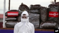 A police wearing a personal protective equipment stands in front of seized illegal drugs before being burnt during a destruction ceremony to mark International Day against Drug Abuse and Illicit Trafficking outside Yangon, Myanmar, Friday, June 26,…