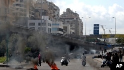 Protesters burn tires to block a road in Beirut, Lebanon, March 8, 2021, as daylong protests intensified amid crash in the local currency, increase of consumer goods prices and political bickering of rival groups delaying the formation of new government.