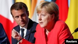 FILE - French President Emmanuel Macron and German Chancellor Angela Merkel attend a news conference following talks on European Union integration, defense and migration at the Elysee Palace in Paris, Aug. 28, 2017.