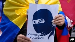 ARCHIVO - Un estudiante universitario con una bandera ecuatoriana y un cartel con un mensaje que dice: "Fuertes y firmes" participa en una marcha para protestar contra los recortes presupuestarios del gobierno, en Quito, Ecuador, el jueves 25 de noviembre de 2021.