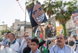 Palestinian protesters carry posters, one reads "no for terrorizing the children," during a protest supporting the children in Gaza, in the West Bank city of Ramallah, May 20, 2021.