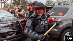 Police officers take cover as they clash with protesters after an officer shot and killed a black man in Brooklyn Center, Minneapolis, Minnesota on April 11,2021. 