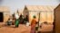 FILE - Displaced women prepare food in the Kaya camp, 100 kms north of Ouagadougou, Burkina Faso, Feb. 8, 2021.
