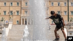 FILE - A boy cools himself in a fountain of the central Syntagma square in front of the Greek parliament during a hot day in Athens, Friday, July 14, 2023. 