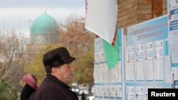 A man reads election candidates posters during parliamentary election in Tashkent, Uzbekistan, Dec. 22, 2019.