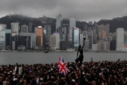 FILE - Protesters carrying the British flag march near the harbor of Hong Kong, July 7, 2019.