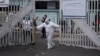 Un trabajador utilizando un traje protector, cierra la puerta principal de la unidad para el coronavirus del hospital San Juan de Dios en la ciudad de Guatemala.