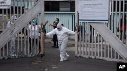 Un trabajador utilizando un traje protector, cierra la puerta principal de la unidad para el coronavirus del hospital San Juan de Dios en la ciudad de Guatemala.