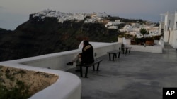 A tourist sits at Firostefani as Greek authorities are taking emergency measures in response to intense seismic activity on the popular Aegean Sea holiday island of Santorini, southern Greece, Feb. 3, 2025.