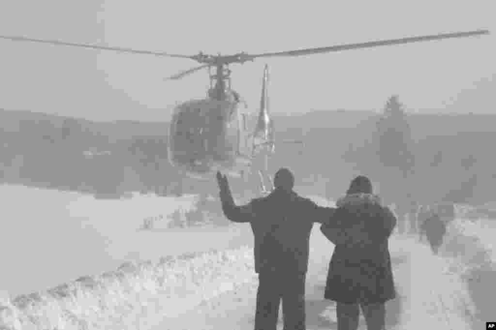 Bosnian people waving to helicopter crew as they wait for food supplies in a remote village, cut off by road due high snow fall, near Bosnian town of Sokolac, 70 kms east of Sarajevo, Bosnia, on February 1, 2012 (AP)