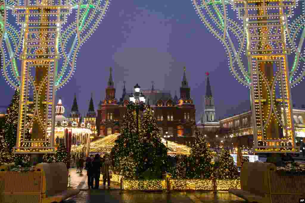 La gente camina en la Plaza Manezhnaya decorada para las celebraciones de Navidad y Año Nuevo cerca de la Plaza Roja con el Museo Histórico y la Muralla del Kremlin al fondo en Moscú, Rusia. 