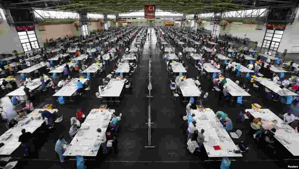 About 1,400 electoral officials sort ballot papers after the conclusion of voting in the European Parliament elections at the Messe in Munich, Germany.