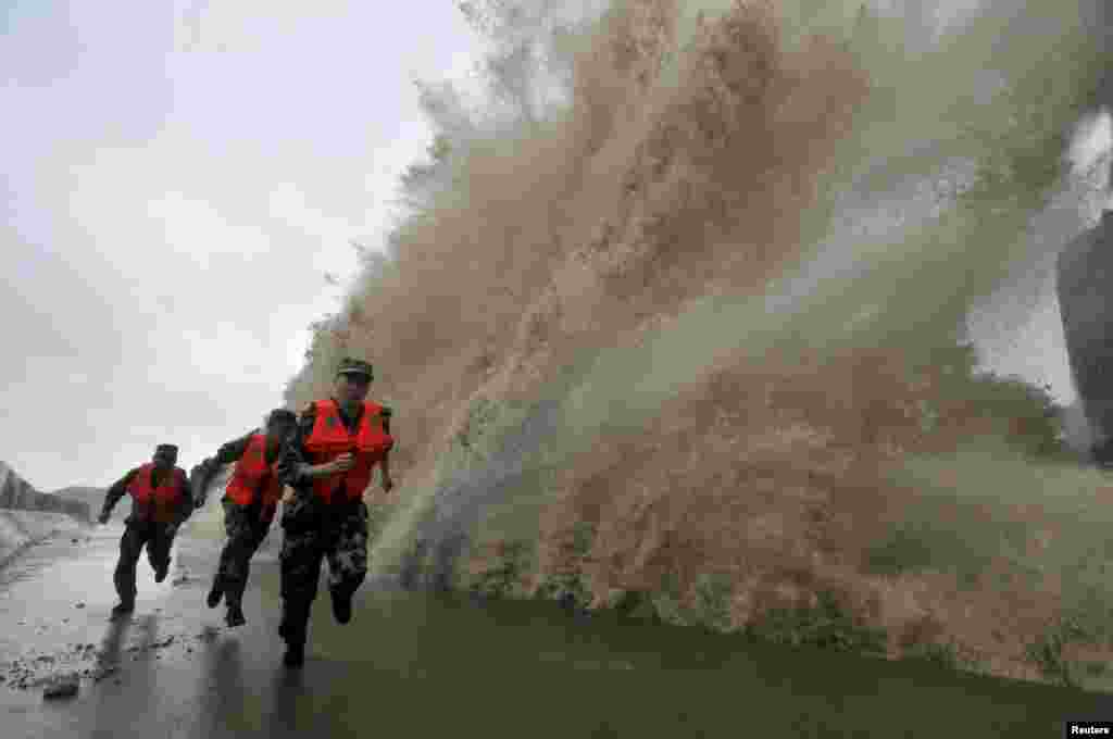 Para tentara berlari saat gelombang besar yang dipicu oleh topan Fitow menghantam garis pantai di Wenling, provinsi Zhejiang (6/10).