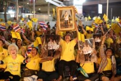 Supporters of the Thai monarchy hold images King Maha Vajiralongkorn and Queen Suthida at a ceremony to mark an anniversary of the death of King Vajiravudh in Bangkok, Thailand, Nov. 25, 2020.