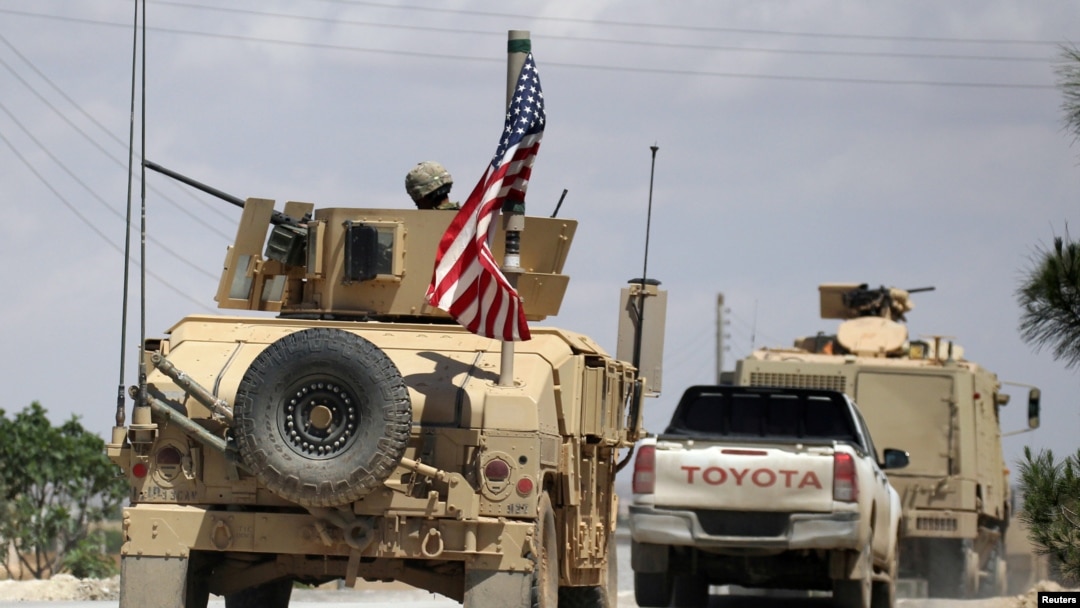 FILE - The U.S. flag flutters on a military vehicle in Manbij countryside, Syria, May 12, 2018.
