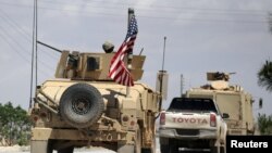 FILE - The U.S. flag flutters on a military vehicle in Manbij countryside, Syria, May 12, 2018. 