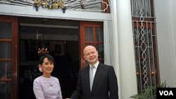 Ikon demokrasi Burma Aung San Suu Kyi (kiri) berjabat tangan dengan Menlu Inggris William Hague di depan kediaman duta besar Inggris di Yangon (5/1)