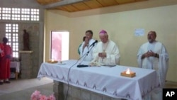 This photo released by Vicenza Diocese, Saturday April 5, 2014 shows Vicenza Bishop Beniamino Pizziol, center, flanked by father Gianantonio Alllegri, right, and Giampaolo Marta, left, during a mass in Tchakidjebe church, near Maroua, Cameroon, during a 