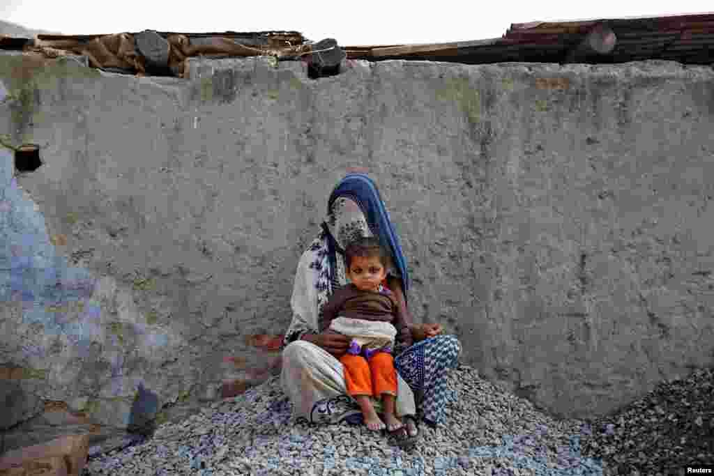 A woman rests with her child while working as a day laborer in Delhi, India.