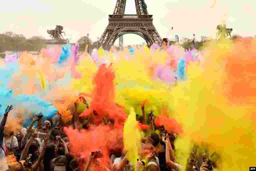 People throw colored powder as they celebrate finishing their five kilometers in the Color Run 2018 at the Eiffel Tower in Paris, France.