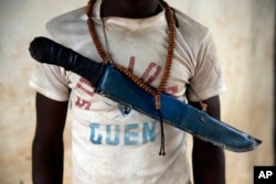 FILE - An Anti-Balaka Christian fighter stands on the front of a looted Muslim store in Guen, some 250 kilometers north of Bangui, Central African Republic,April 15, 2014.