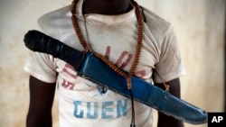FILE - An Anti-Balaka Christian fighter stands on the front of a looted Muslim store in Guen, some 250 kilometers north of Bangui, Central African Republic,April 15, 2014.