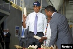 FILE - U.S. President Barack Obama shows off a ear of corn grown by a farmer, second right, participating in the Feed the Future program as he tours the Faffa Food factory in Addis Ababa, Ethiopia, July 28, 2015.