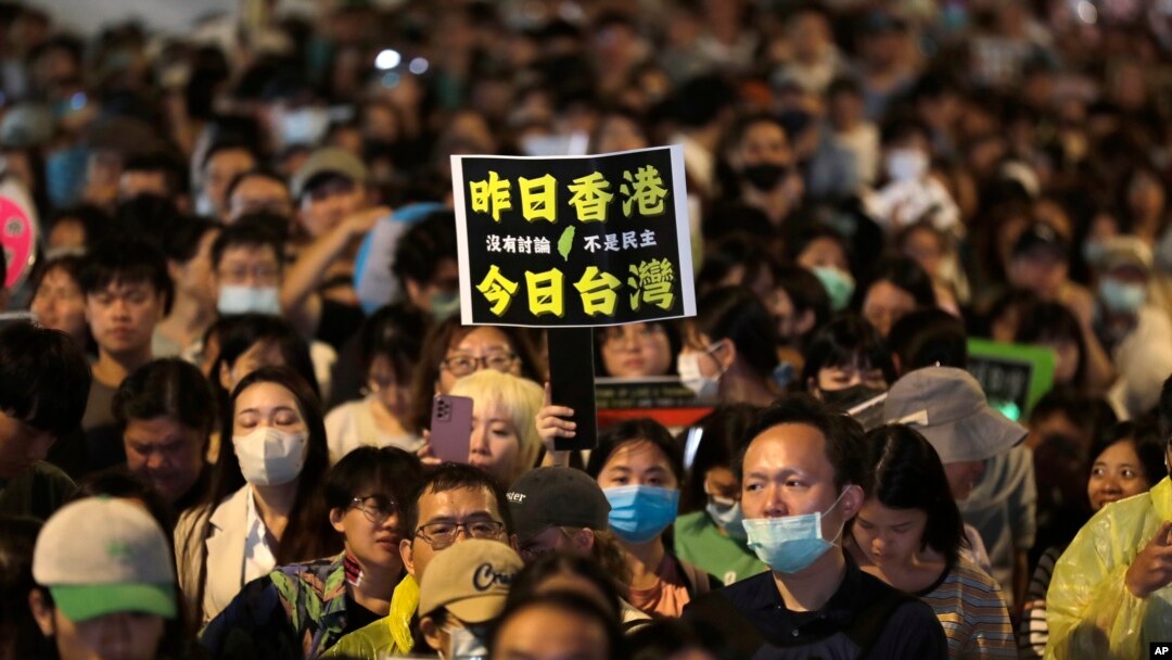 Seorang demonstran membawa poster bertuliskan "Kemarin Hong Kong. Sekarang Taiwan," dalam aksi protes di luar gedung parlemen di Taipei, Taiwan, pada 28 Mei 2024. (Foto: AP/Chiang Ying-ying)