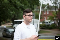 Esta foto del sábado, 12 de agosto de 2017, muestra a James Alex Fields Jr. parado en una acera mirando la procesión del clero mientras supremacistas blancos se reunían en el parque McGaffey, antes de una protesta en Charlottesville, Virginia. Fields lanzó su coche contra una multitud de activistas anti racismo, causando la muerte de Heather Heyer e hiriendo a decenas más.