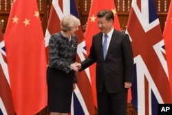 FILE - Chinese President Xi Jinping, right, shakes hand with British Prime Minister Theresa May, prior to their meeting, at the West Lake State House, in Hangzhou, China, Sept. 5, 2016.