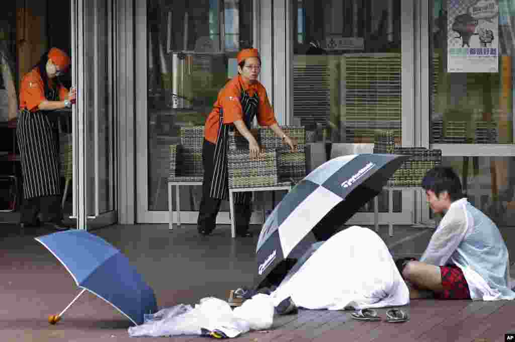 Cafe employees work around pro-democracy student protesters camping at their storefront in the financial district of Hong Kong, Oct. 5, 2014.