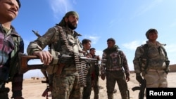 Syria Democratic Forces fighters carry their weapons in a village on the outskirts of al-Shadadi town, Hasaka countryside, Syria, Feb. 19, 2016. 