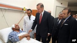 Turkish prime minister Recep Tayyip Erdogan (C) speaks with a wounded police officer at a hospital in Ankara on May 6, 2011