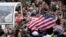 Faithful display a flag of the United States as Pope Francis kisses an infant from his pope-mobile during his tour through the crowd for his weekly general audience in St. Peter's Square at the Vatican, March 23, 2016.