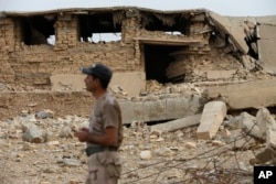 An Iraqi soldier stands in front a damaged part of the ancient site of Nimrud, which was destroyed by Islamic State militants, some 19 miles (30 kilometers) southeast of Mosul, Iraq, Nov. 16, 2016.