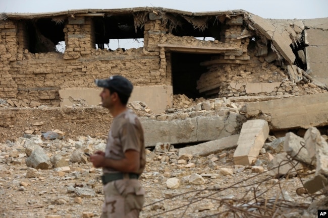 An Iraqi soldier stands in front a damaged part of the ancient site of Nimrud, which was destroyed by Islamic State militants, some 19 miles (30 kilometers) southeast of Mosul, Iraq, Nov. 16, 2016.