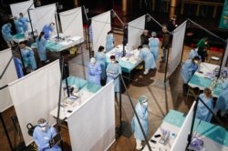 Health care workers prepare to collect coronavirus swab samples from concertgoers at the Palau Sant Jordi, in Barcelona, Spain, March 27, 2021.